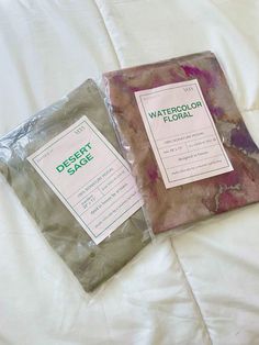 two bags of watercolor floal sitting on top of a white bed sheet