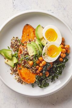 a white plate topped with an egg, avocado and chickpeas salad