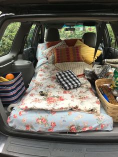 the back end of a car with an open trunk filled with blankets, pillows and other items