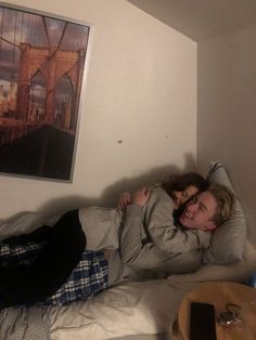 two people laying in bed hugging each other