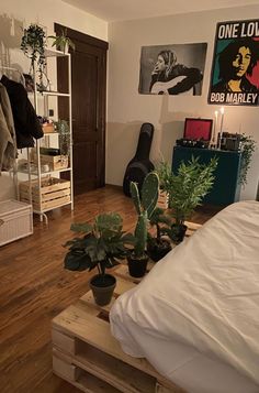 a room filled with lots of plants and pictures on the wall next to a bed