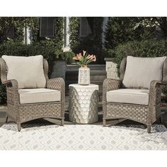 two chairs sitting next to each other on top of a white and beige rug in front of a house