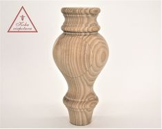 a tall wooden vase sitting on top of a white table next to a red triangle