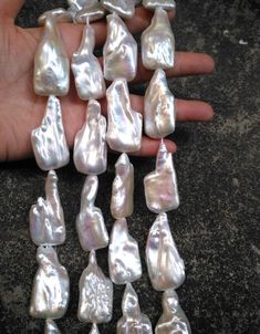 a hand is holding several different types of pearls