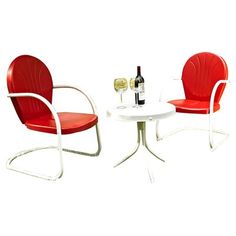 two red chairs and a white table with a bottle of wine on it next to each other