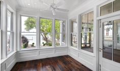 an empty room with wood flooring and white trim on the windows, along with wooden floors