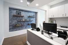 an office with two computer monitors on the desk and shelves in the wall behind it