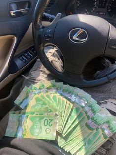 a bunch of money sitting in the passenger seat of a car next to a steering wheel