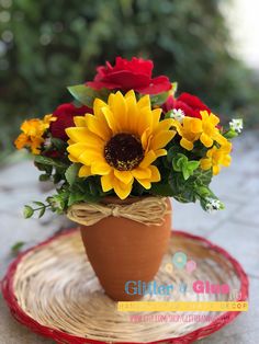 a potted plant with sunflowers and roses in it sitting on a plate