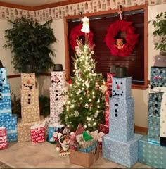 a christmas tree is surrounded by presents in boxes and wrapped around the snowman's head