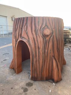 a large tree trunk with a hole in it's center, and a parking lot behind it