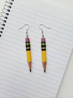 a pair of pencil earrings sitting on top of a notebook