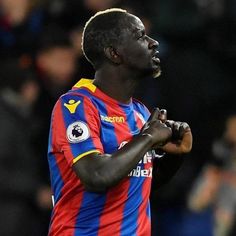 a soccer player is looking up at the sky with his hand on his chest and eyes closed