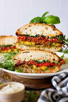 two sandwiches stacked on top of each other with lettuce and tomato toppings