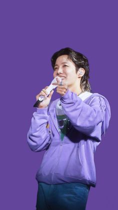 a woman brushing her teeth with an electric toothbrush in front of a purple background