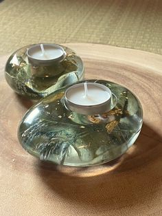 two glass candles sitting on top of a wooden table