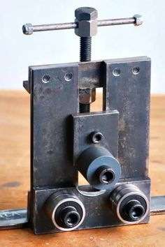 a metal object with two wheels on top of it, sitting on a wooden table