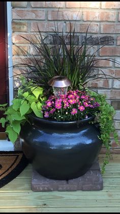 a large potted planter with flowers and plants in it sitting on a porch