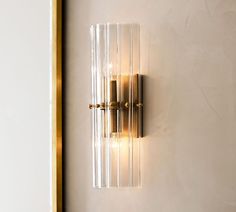 a wall mounted light with two lights on it's side and a mirror behind it