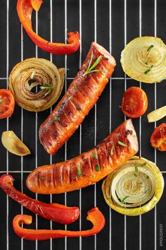 sausages, onions, and peppers on a grill grate with some seasoning