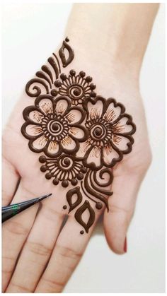 a woman's hand with henna on it and a pen next to it