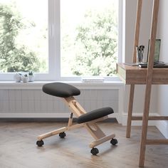 a black chair sitting in front of a window next to a wooden desk with a laptop on it