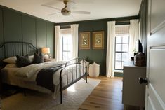 a bed room with a neatly made bed next to two windows and a ceiling fan