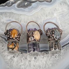 three glass vases with different types of stones in them sitting on a marble slab