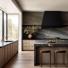 a large kitchen with marble counter tops and wooden cabinets, along with two bar stools