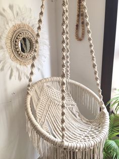 a white hanging chair next to a potted plant