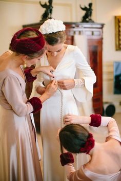 two women in dresses are fixing the bride's necklace