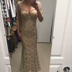 a woman taking a selfie in a mirror wearing a gold evening gown and jacket