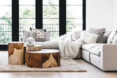 a living room with couches, tables and pillows on the floor in front of large windows