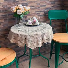 a table and two chairs in front of a brick wall with flowers on the table