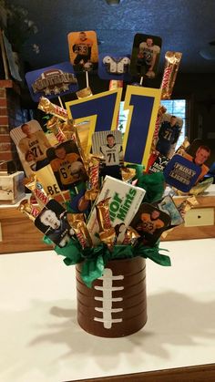 a football themed arrangement in a vase on a table with pictures and candies all over it