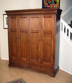 a large wooden cabinet sitting in the corner of a room next to a stair case