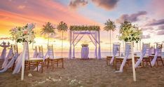 an outdoor wedding set up on the beach with white chairs and floral arrangements at sunset