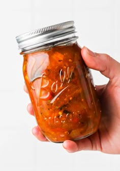 a hand holding a mason jar filled with food