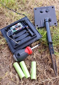 an electronic device is laying on the ground next to some batteries and other items that have been placed around it