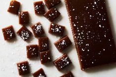 there are many pieces of chocolate on the table with white flakes around it and one piece has been cut into cubes