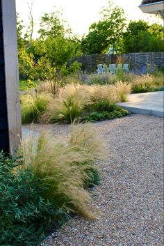 a garden with gravel and grass next to a house