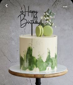 a white cake with green icing and two macaroons sitting on top of it