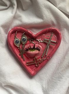 a pink heart with eyes and cross charms