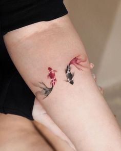 two koi fish tattoo on the right side of the leg, with one red and one black