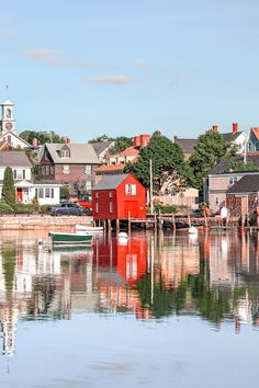 a red house sitting on top of a body of water next to a small boat