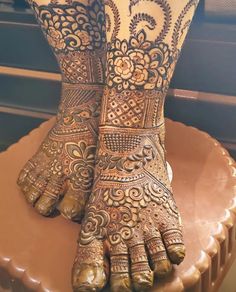 the legs and feet of a woman with henna tattoos on their hands, sitting on top of a cake