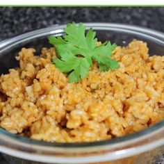 a glass bowl filled with rice and garnished with parsley