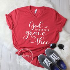 a red shirt that says god shed his grace on the front, and two pairs of sneakers