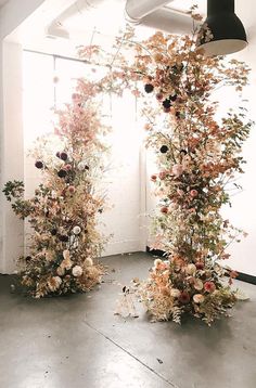 three tall vases filled with flowers sitting on top of a floor next to a window