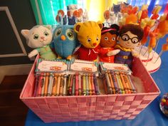 a pink basket filled with lots of crayons and stuffed animals on top of a table